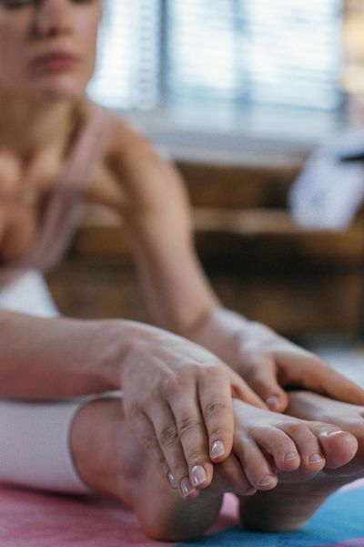 Close-up of hands and feet in a controlled yoga position on a light mat.